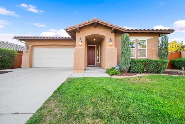 mediterranean / spanish house with a garage and a front lawn