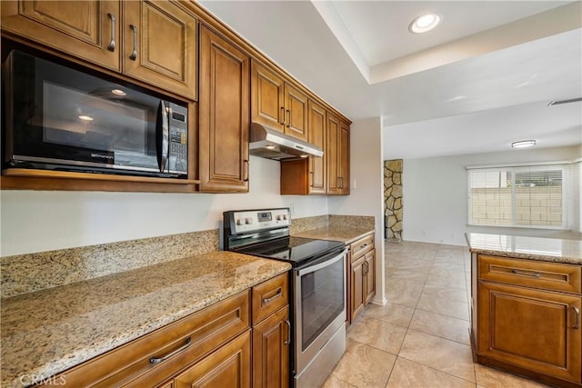 kitchen with light stone counters, a tray ceiling, and stainless steel electric range