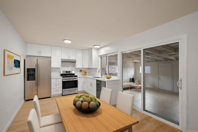 kitchen featuring under cabinet range hood, stainless steel appliances, white cabinets, and a sink