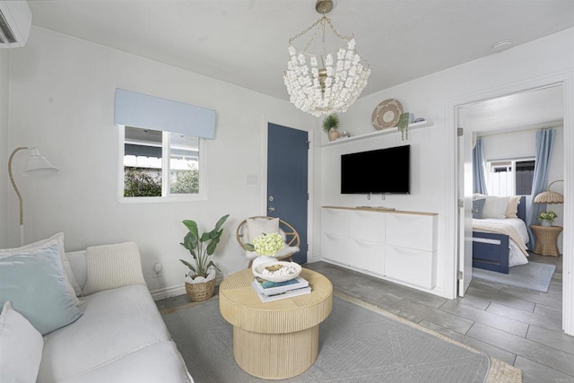 living room with a chandelier, a wall unit AC, and a wealth of natural light