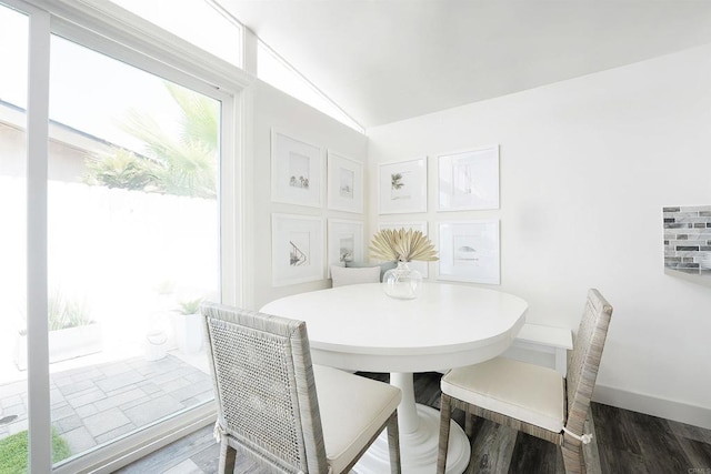 dining room with lofted ceiling, a wealth of natural light, and dark hardwood / wood-style flooring