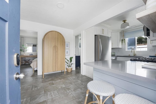 kitchen with sink, stainless steel fridge, range, tasteful backsplash, and white cabinets