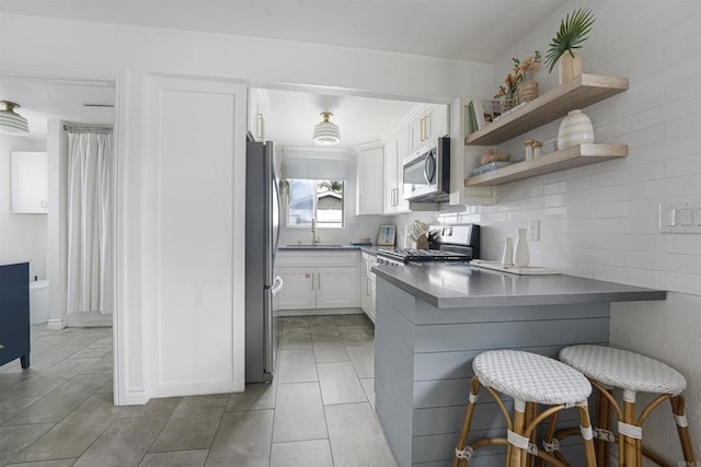 kitchen featuring a breakfast bar, sink, white cabinetry, kitchen peninsula, and stainless steel appliances