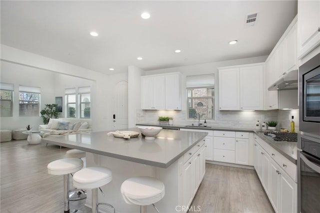 kitchen featuring sink, extractor fan, white cabinetry, a center island, and appliances with stainless steel finishes