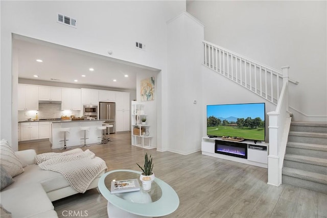 living room with a towering ceiling and light hardwood / wood-style floors