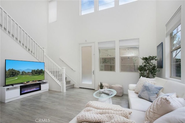 living room with a towering ceiling, stairway, and wood finished floors