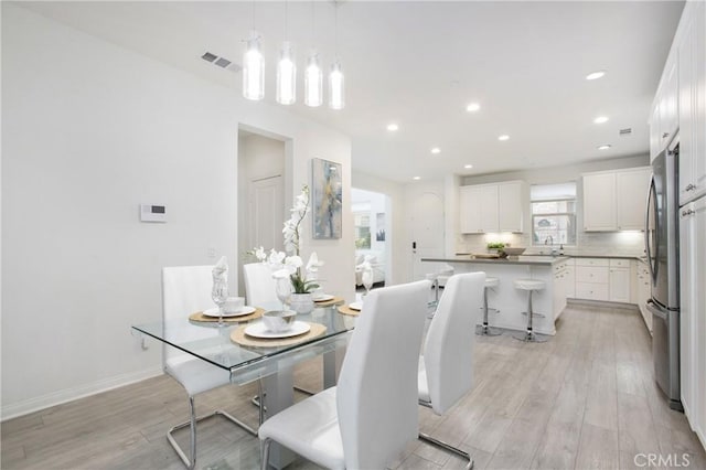 dining space with sink and light hardwood / wood-style floors