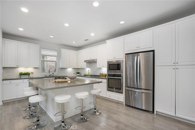 kitchen featuring stainless steel appliances, white cabinetry, sink, and a kitchen breakfast bar