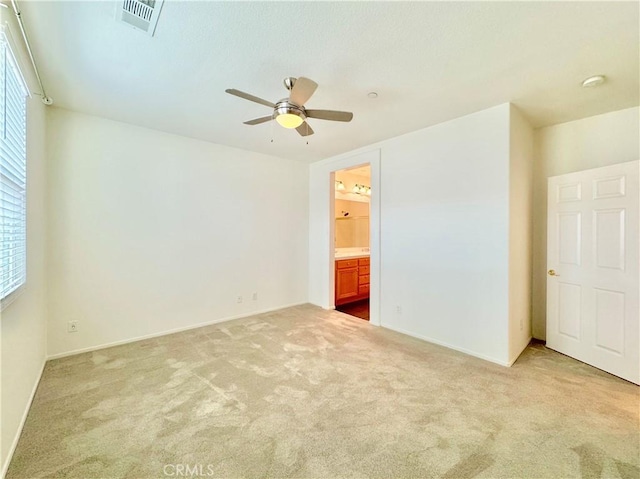 unfurnished bedroom with ceiling fan, light colored carpet, and connected bathroom