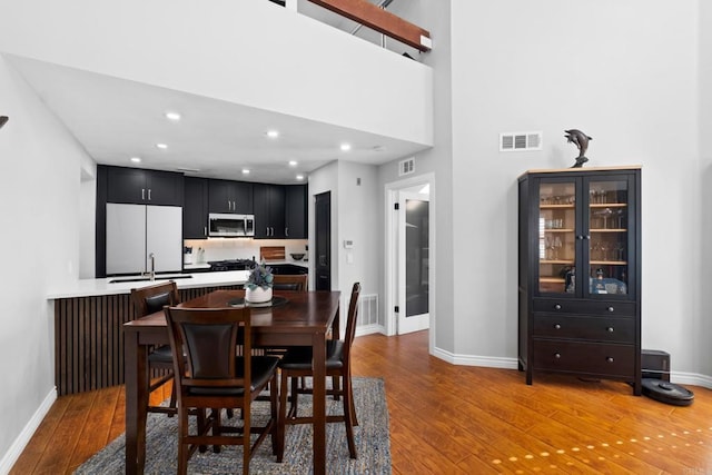 dining room featuring hardwood / wood-style floors, sink, and a high ceiling