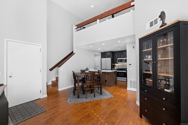 dining area featuring a towering ceiling and light hardwood / wood-style floors