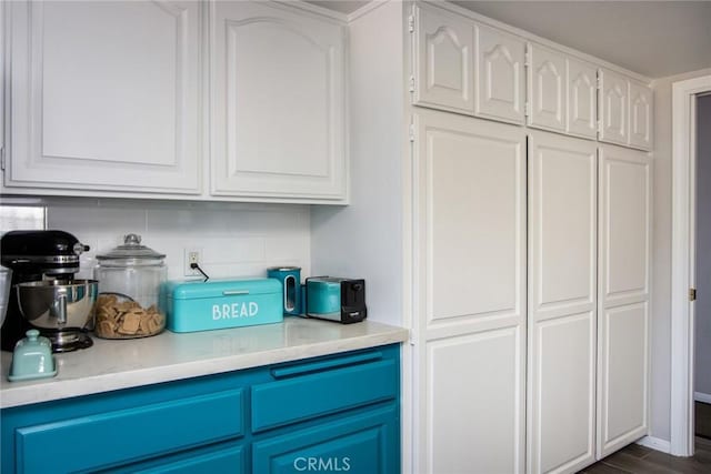 interior space featuring tasteful backsplash, white cabinetry, dark hardwood / wood-style floors, and blue cabinetry