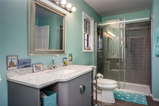 bathroom with hardwood / wood-style flooring, vanity, toilet, and walk in shower