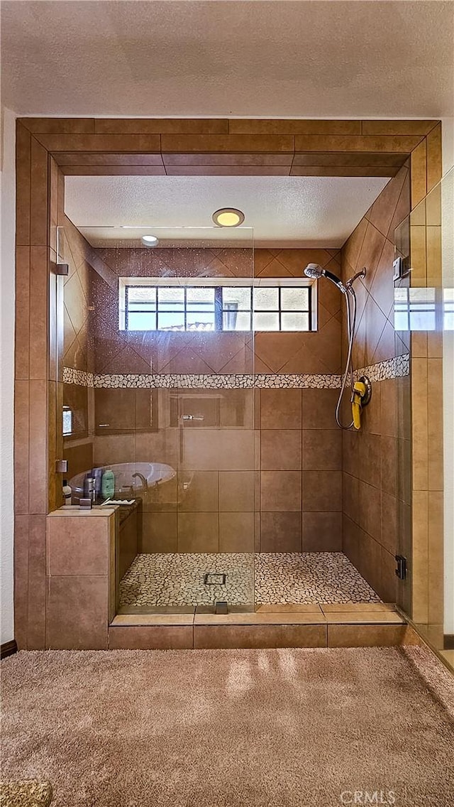 bathroom with a wealth of natural light, a textured ceiling, and walk in shower