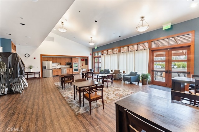 dining space with hardwood / wood-style flooring, plenty of natural light, high vaulted ceiling, and french doors