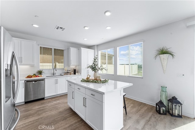 kitchen featuring white cabinetry, stainless steel appliances, sink, and a kitchen island