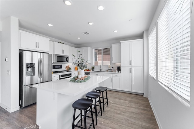 kitchen featuring a kitchen island, sink, a breakfast bar area, white cabinets, and stainless steel appliances