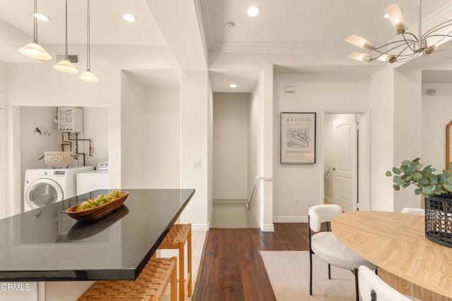 dining room with water heater, ornamental molding, washing machine and clothes dryer, dark hardwood / wood-style flooring, and a chandelier