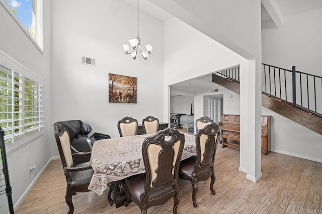 dining room featuring light hardwood / wood-style flooring, a chandelier, and a high ceiling