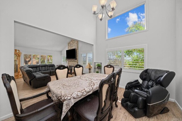 dining space featuring an inviting chandelier, a towering ceiling, and light wood-type flooring
