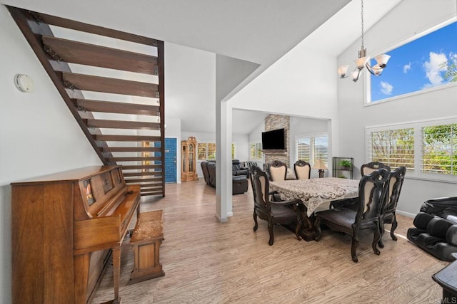dining space with high vaulted ceiling, light hardwood / wood-style floors, and a notable chandelier
