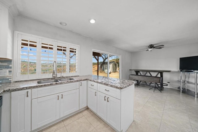 kitchen with white cabinetry, sink, light tile patterned floors, and stone counters