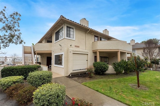 mediterranean / spanish home featuring a balcony, stairs, stucco siding, a chimney, and a front yard