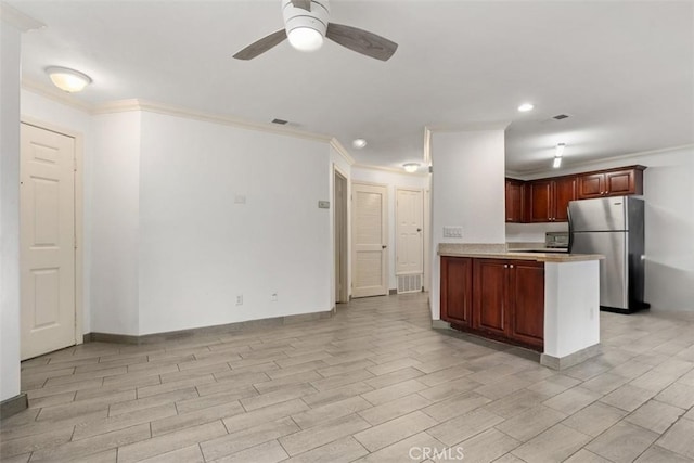 kitchen with a peninsula, light countertops, crown molding, and freestanding refrigerator