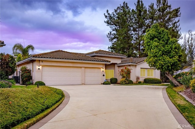 view of front of house with a tile roof, stucco siding, concrete driveway, and a garage