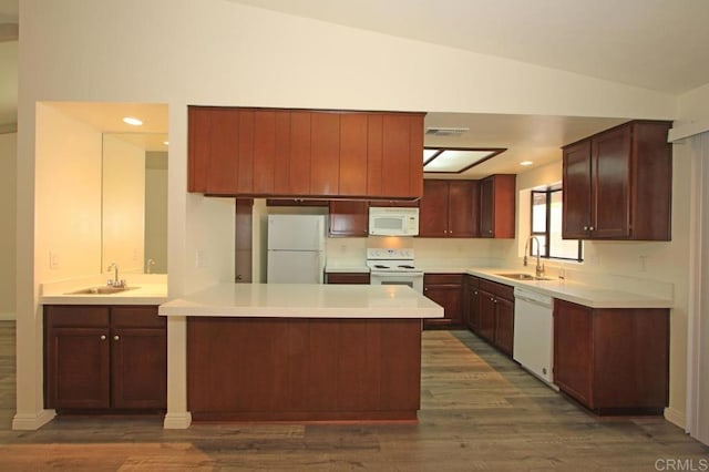 kitchen with sink, dark wood-type flooring, white appliances, and kitchen peninsula