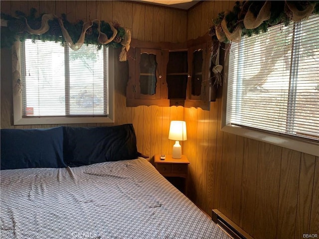 bedroom featuring a baseboard heating unit and wood walls