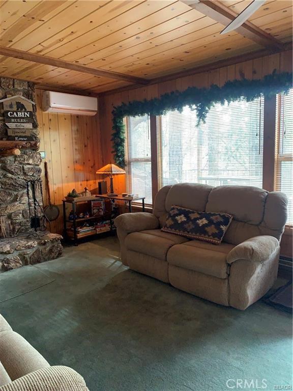 living room featuring wood ceiling, a wall mounted air conditioner, carpet flooring, and wood walls