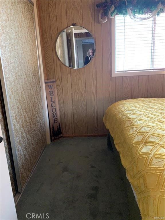 bedroom featuring dark carpet and wood walls