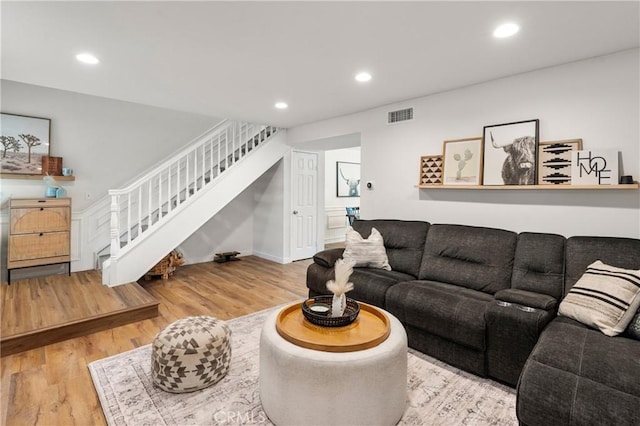 living area with visible vents, recessed lighting, stairs, and wood finished floors