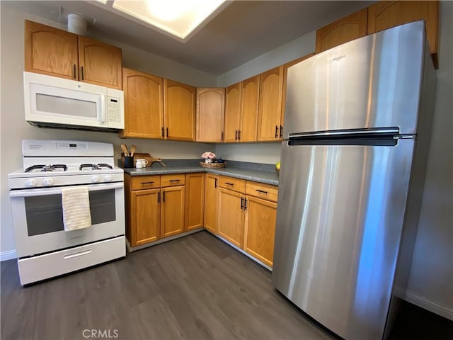 kitchen with white appliances and dark hardwood / wood-style flooring