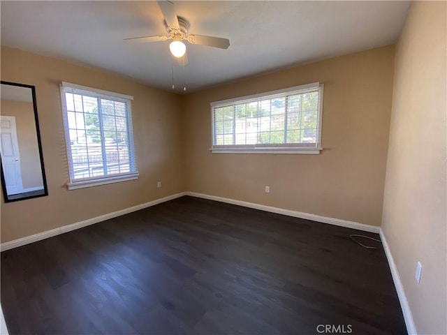 spare room with dark hardwood / wood-style flooring, a wealth of natural light, and ceiling fan