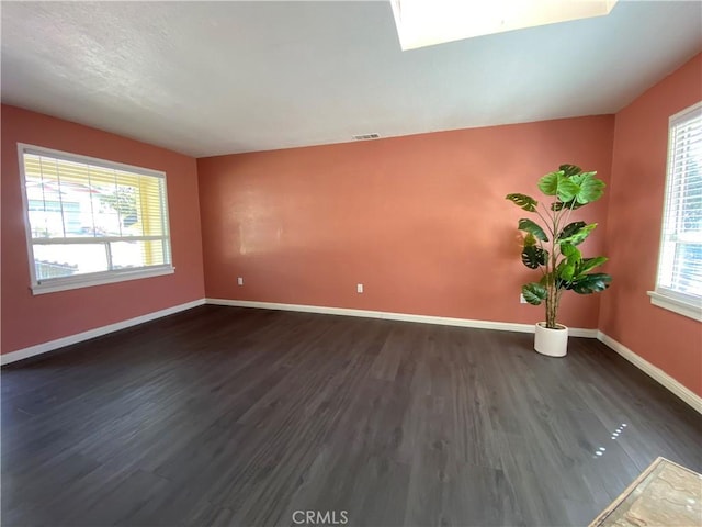 spare room featuring dark hardwood / wood-style floors and a healthy amount of sunlight