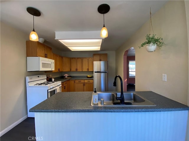 kitchen with sink, white appliances, decorative light fixtures, and kitchen peninsula