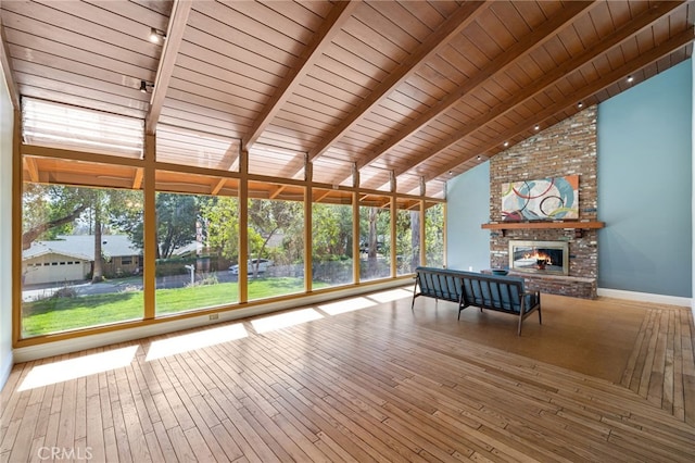 unfurnished sunroom featuring plenty of natural light, lofted ceiling with beams, wood ceiling, and a brick fireplace