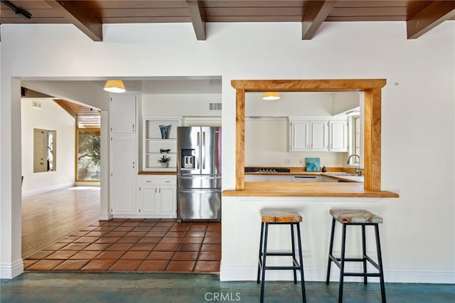 kitchen featuring kitchen peninsula, white cabinets, a kitchen bar, and stainless steel refrigerator with ice dispenser