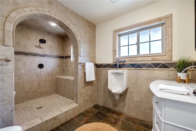 bathroom with tile walls, vanity, and a tile shower