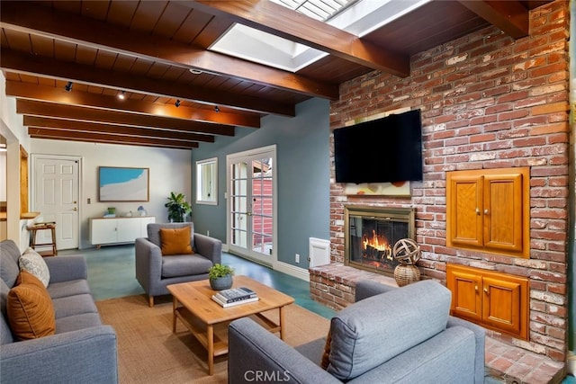 living room featuring beamed ceiling, a brick fireplace, a skylight, and wooden ceiling