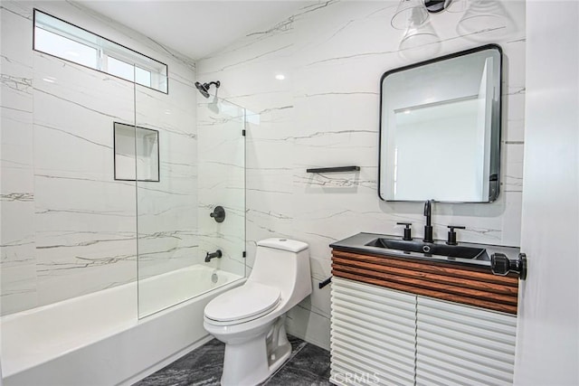 full bathroom featuring tiled shower / bath, vanity, toilet, and tile walls