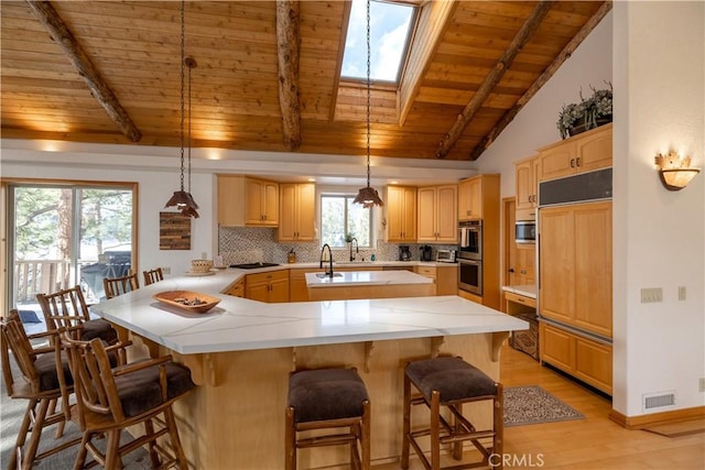 42848 Eagle Flight Pl, Big Bear Lake, CA 92315 - kitchen with backsplash, a kitchen bar, kitchen peninsula, stainless steel appliances, and light brown cabinets
