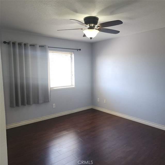 unfurnished room featuring ceiling fan, baseboards, dark wood finished floors, and a textured ceiling