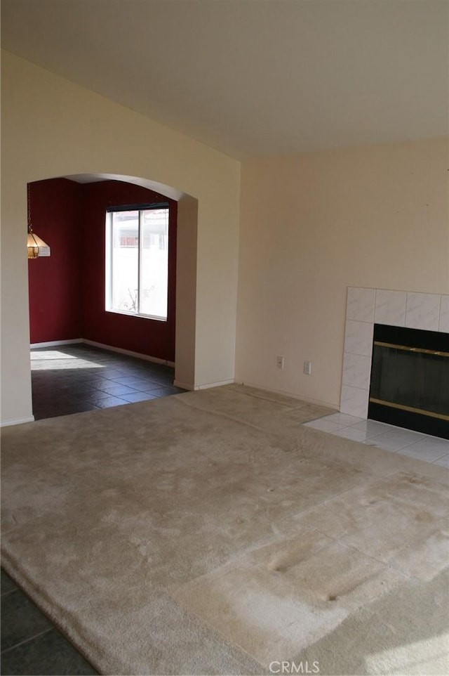 unfurnished living room with a tiled fireplace and carpet floors