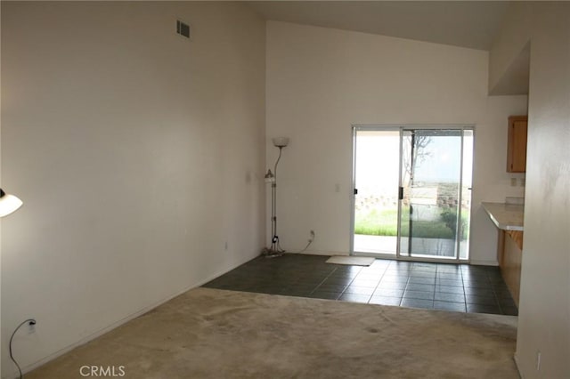 unfurnished room with dark tile patterned flooring and a high ceiling