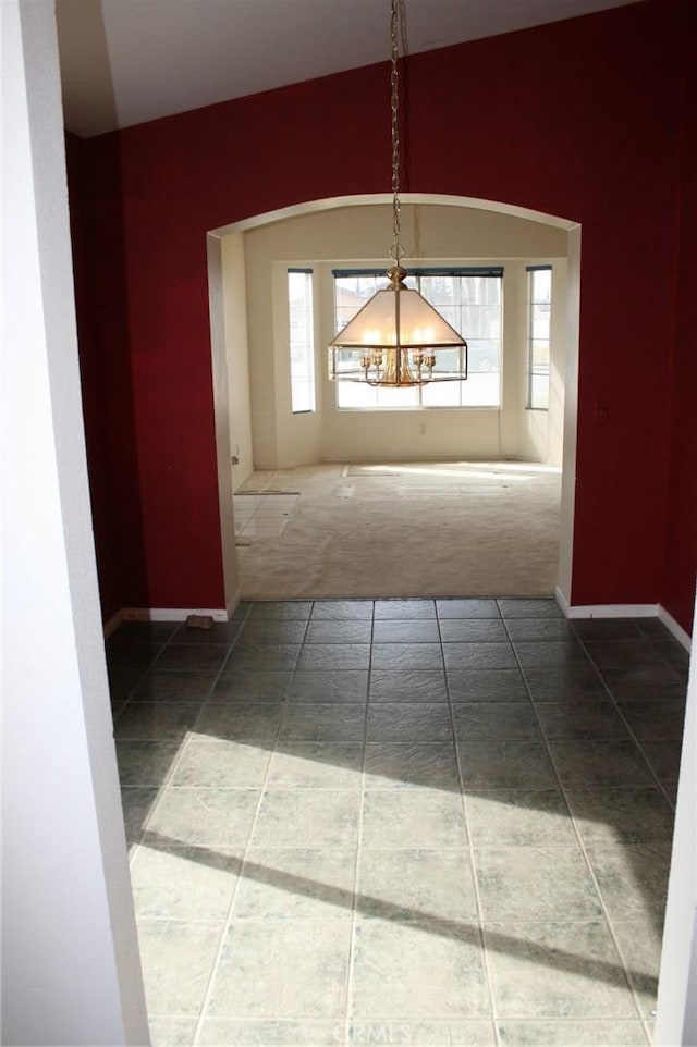 unfurnished dining area featuring carpet and an inviting chandelier