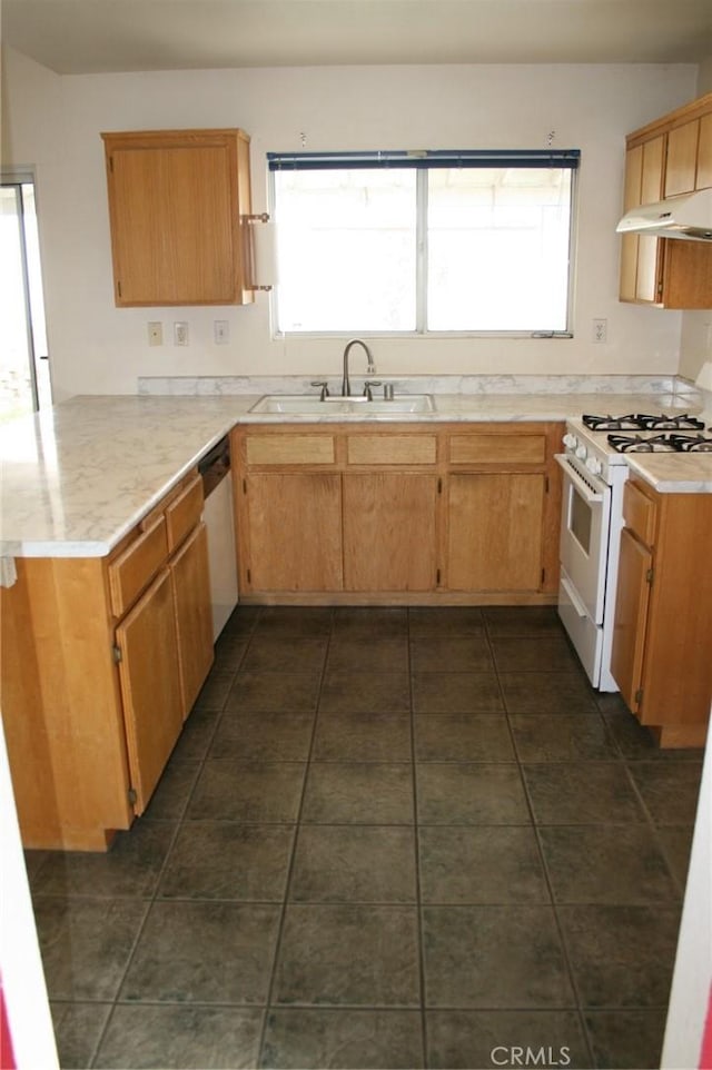 kitchen featuring dishwasher, sink, dark tile patterned flooring, gas range gas stove, and kitchen peninsula