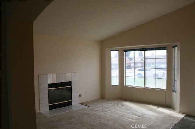 unfurnished living room featuring a tile fireplace, lofted ceiling, and light carpet